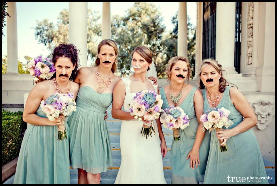 Bridesmaids wearing mustache props at a wedding